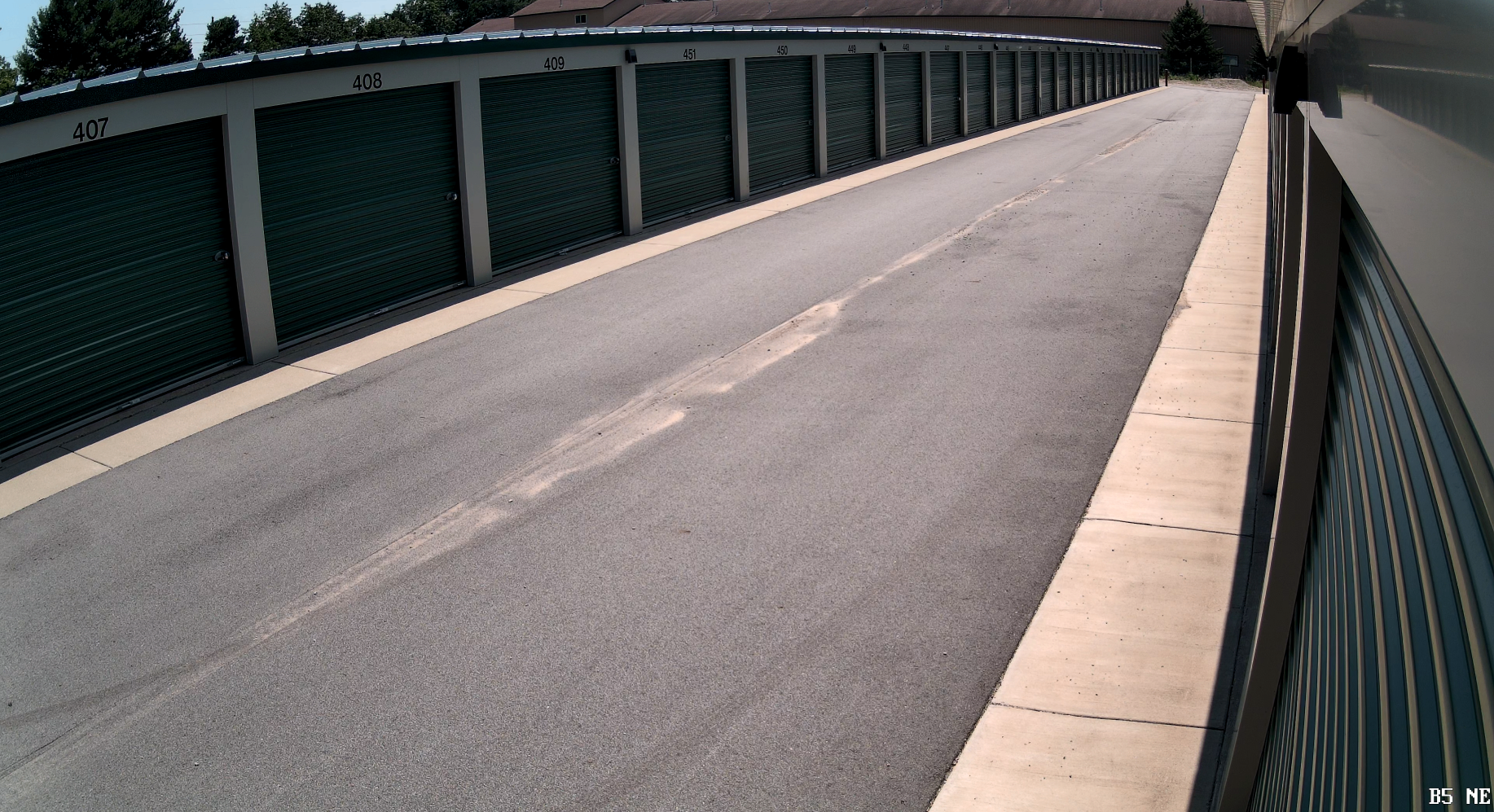 Security camera view down an aisle of self-storage units with roll-up doors